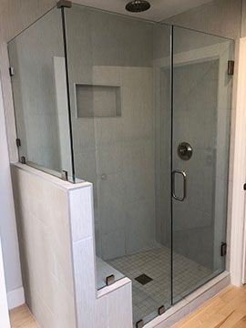 Glass shower enclosure with gray tile and built-in bench.