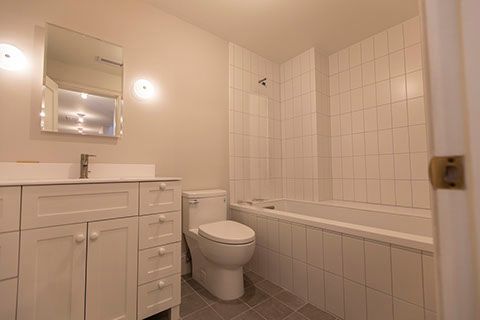 White bathroom with a vanity, toilet, and bathtub.