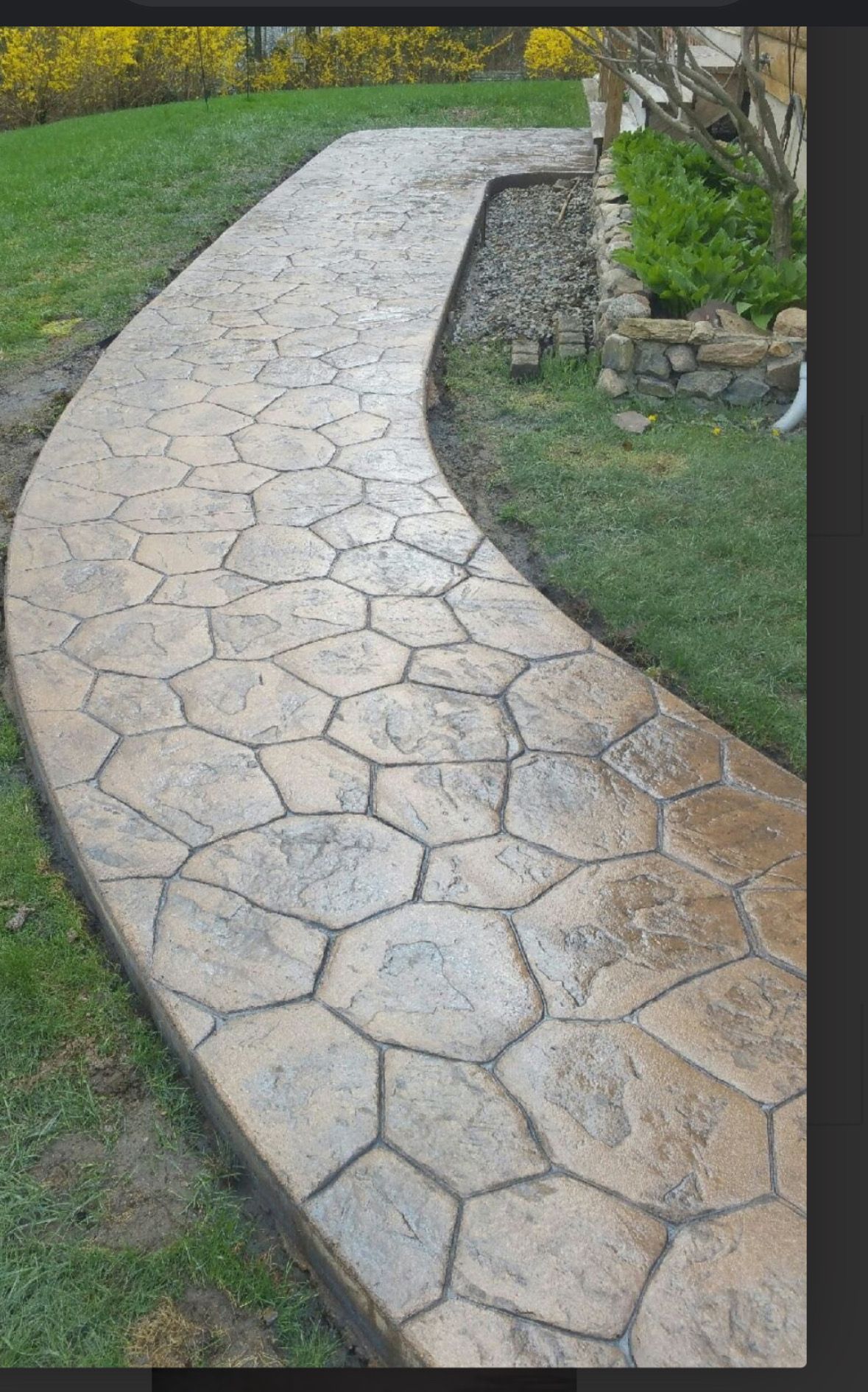 Stamped concrete pathway in a hexagonal stone pattern curves through a grassy yard.