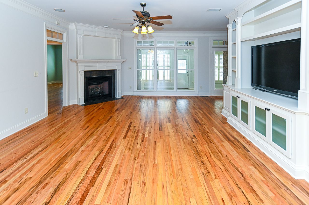 An empty living room with hardwood floors and a fireplace.