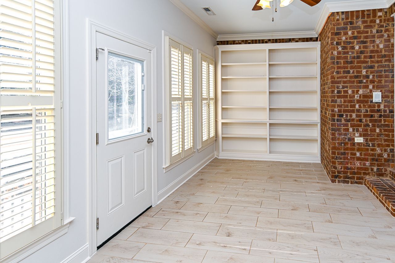 An empty room with a brick wall and white shelves.