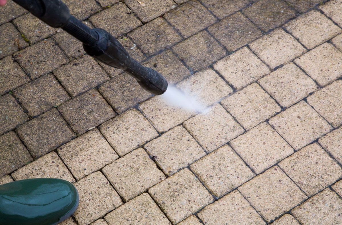 A pressure washing a brick walkway