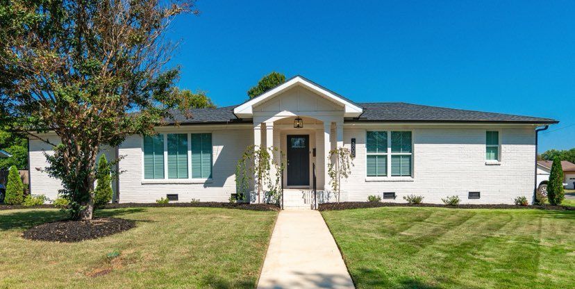 A white house with a black door and a walkway leading to it.