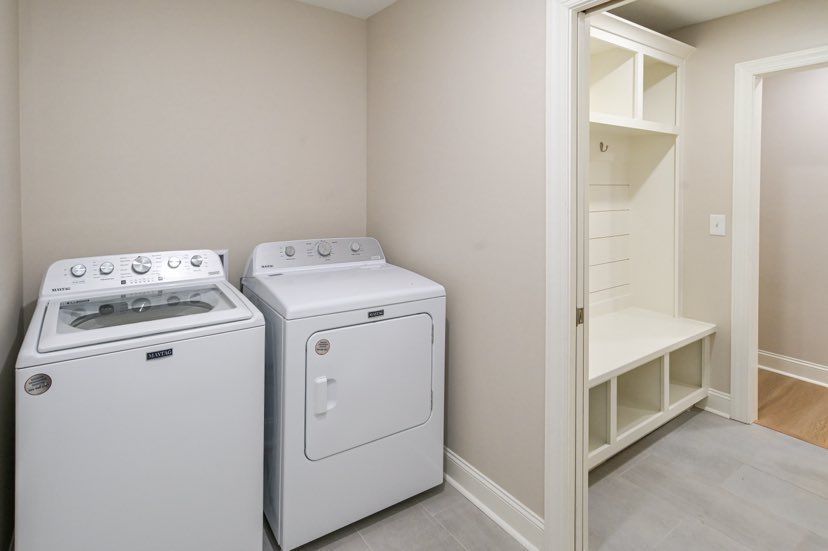 A laundry room with a washer and dryer and a bench.