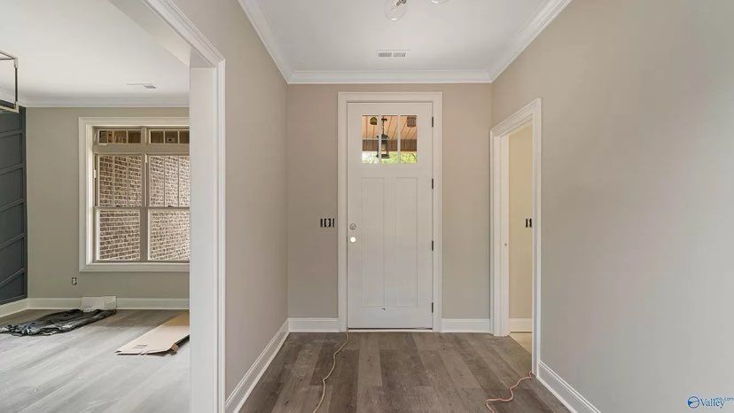 An empty hallway with a white door and a window.