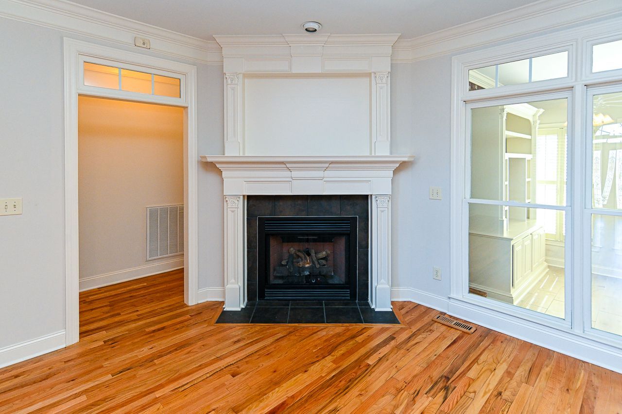 An empty living room with hardwood floors and a fireplace.