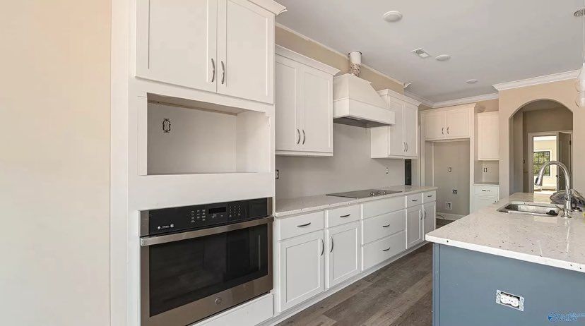 A kitchen with white cabinets, stainless steel appliances, and a blue island.