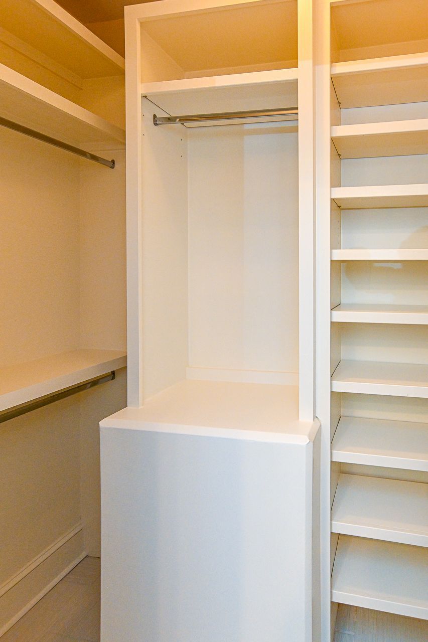 A walk in closet with lots of shelves and a dresser.