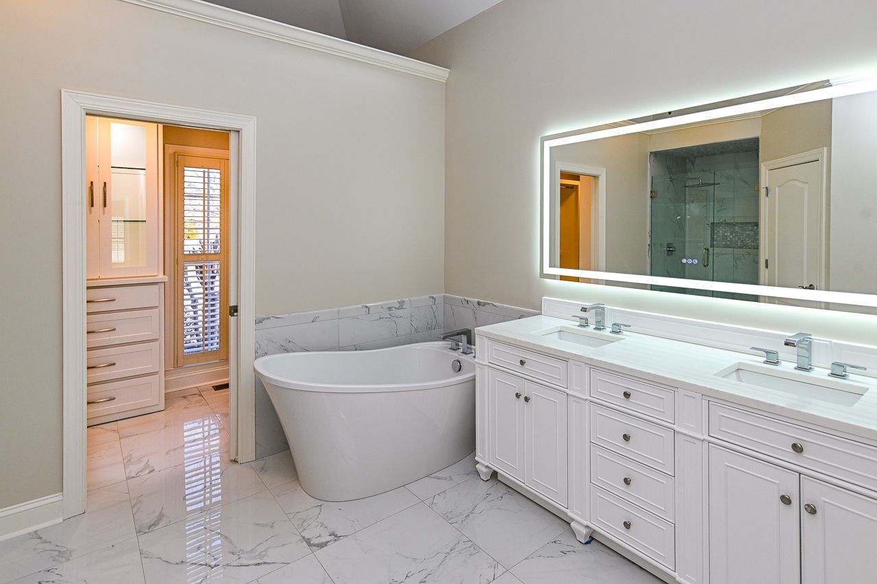 A bathroom with a bathtub, sinks, and a large mirror.