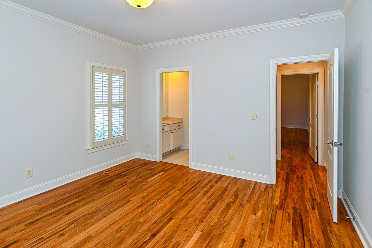 An empty bedroom with hardwood floors and white walls.