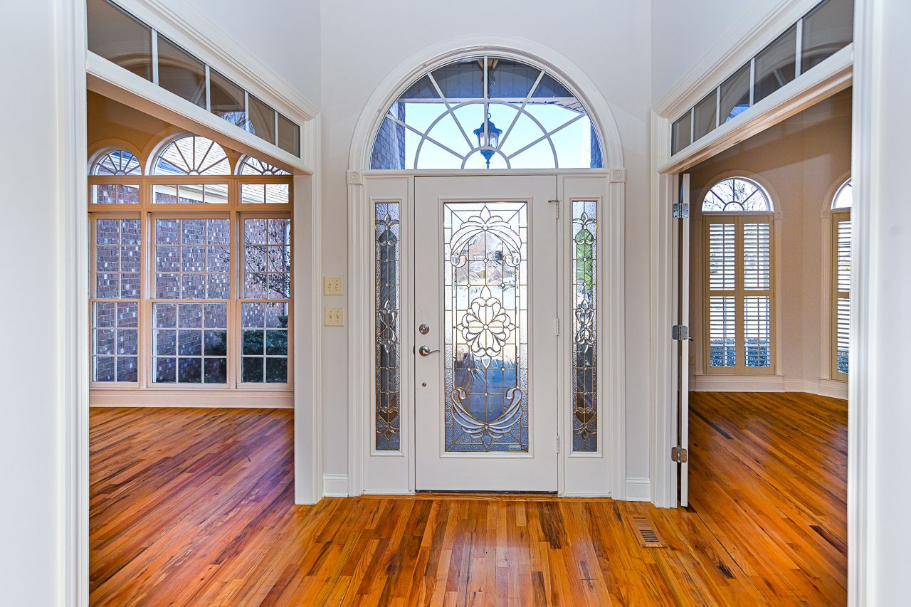 A large empty room with hardwood floors and a stained glass door.