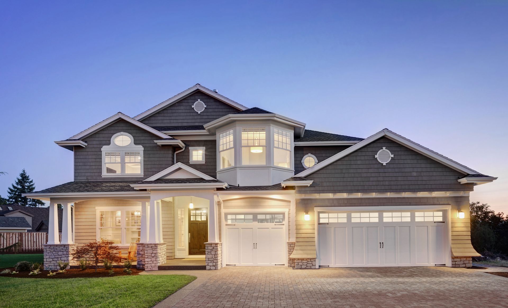 Two-story house with beige siding, white trim, and a two-car garage at dusk.