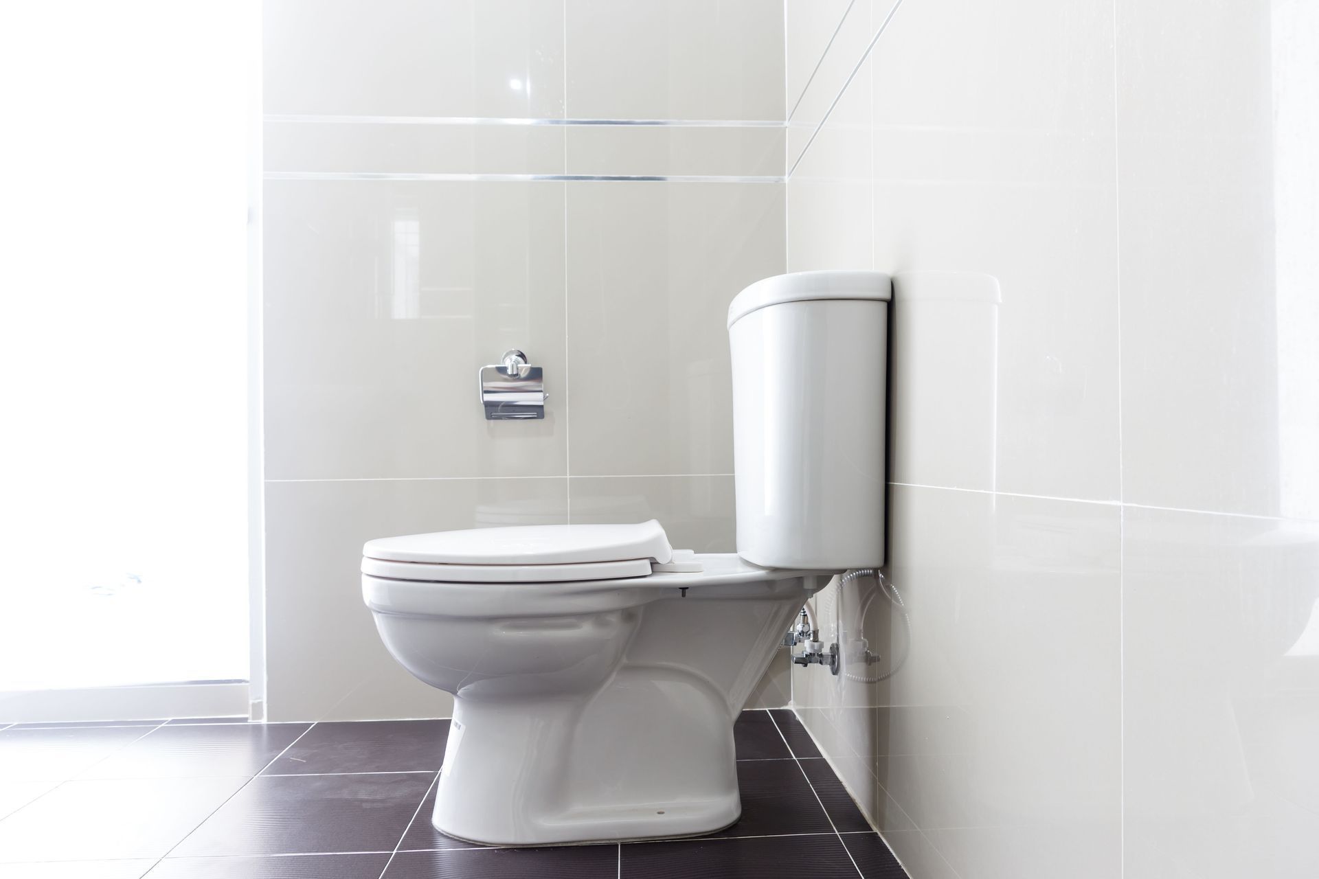 White toilet in a tiled bathroom with a dark floor.