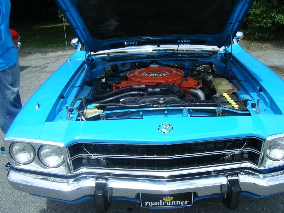 Blue classic car with hood open, showing orange engine in front view