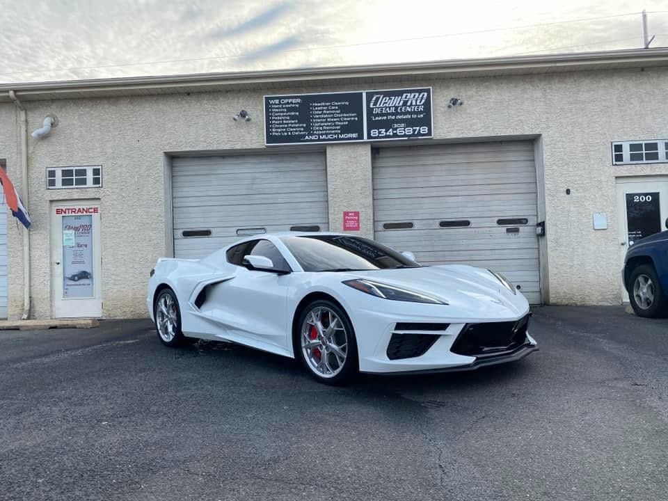 White sports car parked outside a garage with roll-up doors