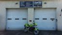 Two white garage doors with a green motorcycle parked in front