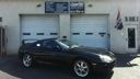 Dark sports car parked in front of a garage at a service station