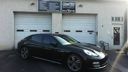 Black sedan parked in front of a white building with a garage door and signage