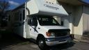White cargo van parked beside a house in a driveway, front view