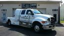 White utility truck parked outside a building, with a logo on the door.