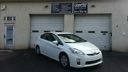 White car parked in front of a garage with closed doors and a building facade
