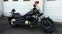 Black custom motorcycle parked on a driveway in front of a house