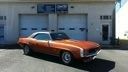 Orange classic car parked outside a building with blue doors and windows