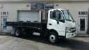 White and blue dump truck parked outside a building with a garage door