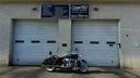 Motorcycle parked in front of two white garage doors with signs above them