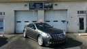 Black car parked in front of a garage with white doors and blue signs