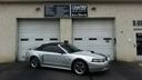 Silver convertible parked in front of a beige garage with closed white doors