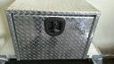 Diamond-plate metal toolbox with a black latch on a concrete floor