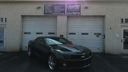 Dark sedan parked in front of a beige garage with two closed doors and a sign above.
