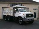 White dump truck parked in front of a beige building