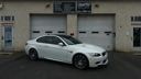 White sedan parked in front of a garage on a residential street