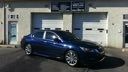 Blue sedan parked outside a building with garage doors at night