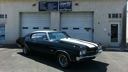 Black classic car parked in front of a building with garage doors