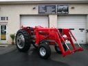 Red tractor with front loader parked outside a building