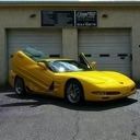 Yellow sports car parked outside a garage with closed white doors.