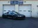Black sports car parked in front of a garage door with signs above it