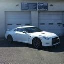 White sports car parked in front of a gray garage door at a building.