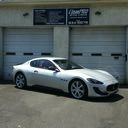 White sports coupe parked outside a garage with two roll-up doors