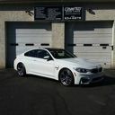 White sports coupe parked in front of garage doors at a commercial building.
