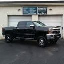 Black pickup truck parked in front of a garage with a building sign above the doors
