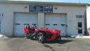 Red sports car parked in front of a white garage door and building.