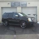 Black SUV parked in front of a garage door on a wet driveway