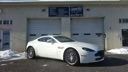 White sports car parked in front of a garage door with a building facade behind it