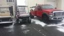 Snow-covered parking lot with three parked vehicles, including a red truck and a silver SUV