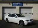White sports sedan parked in front of a garage door under a business sign