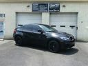 Black sports car parked outside a garage with white doors and a sign above.